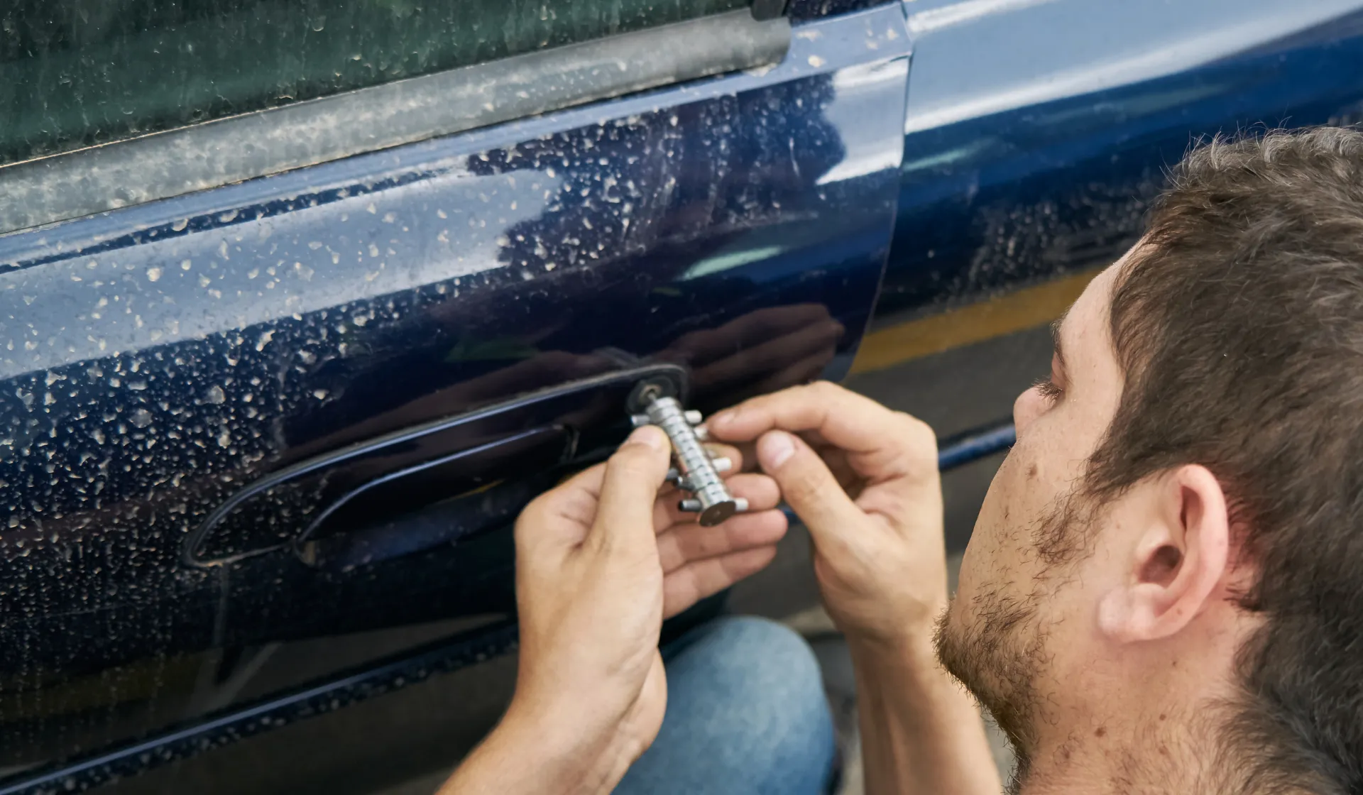 Locksmith using a decoder tool on a blue car door lock, emergency car locksmith Port St. Lucie