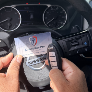 Emergency Pro Locksmith business card next to Nissan steering wheel during automotive locksmith service in Port St. Lucie